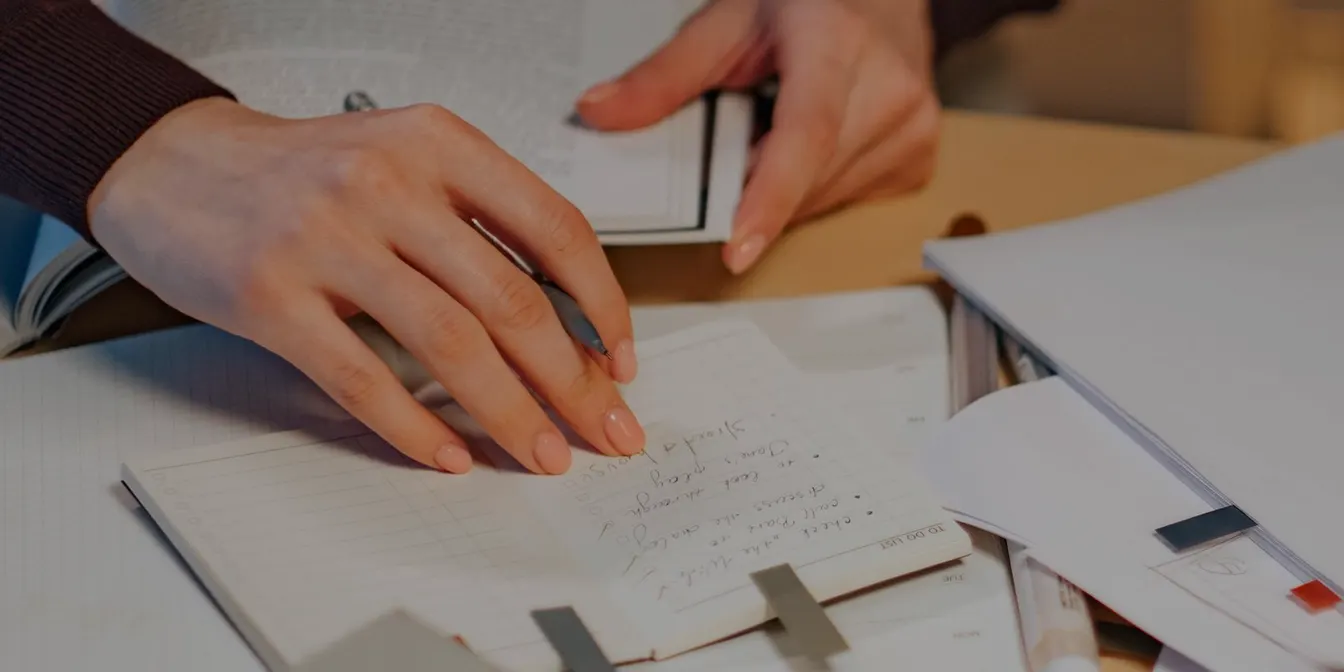 자료와 노트를 펼쳐 두고 손으로 기록을 남기는 책상